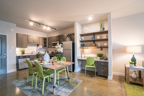 a dining room and kitchen with a table and green chairs