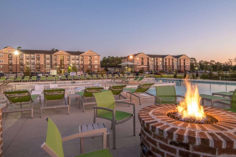 an outdoor patio with a fire pit and chairs at dusk