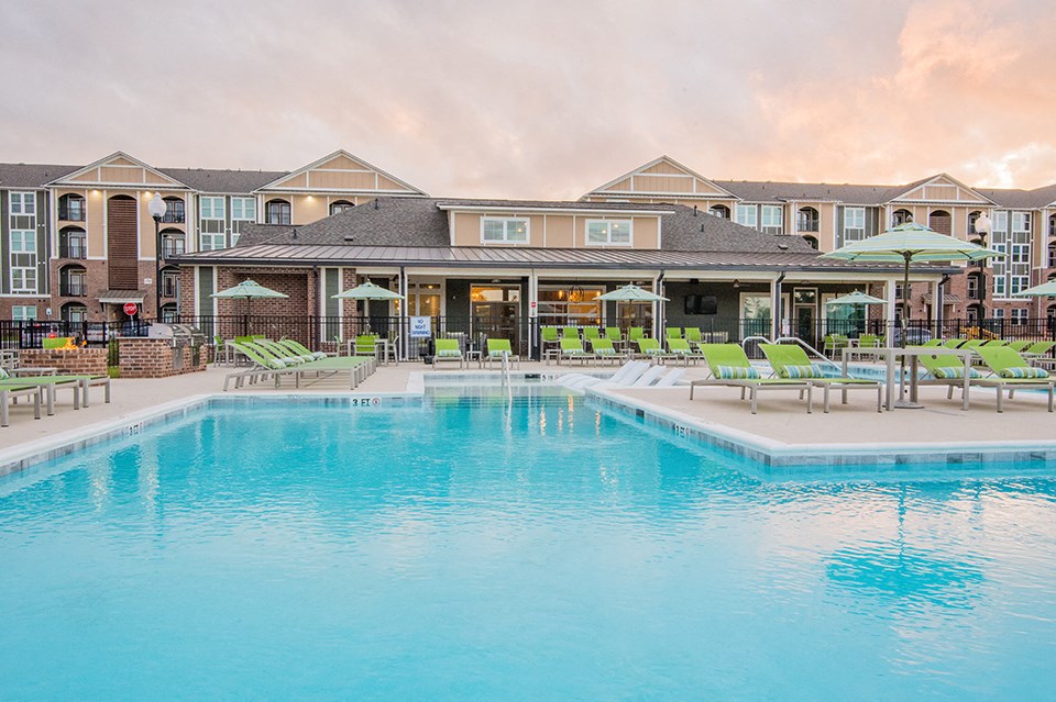 a swimming pool with chairs and umbrellas in front of a building