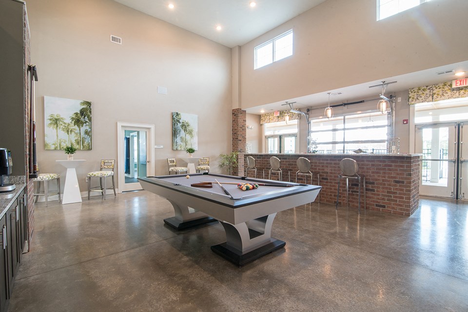 a billiards table in a clubhouse with a bar in the back