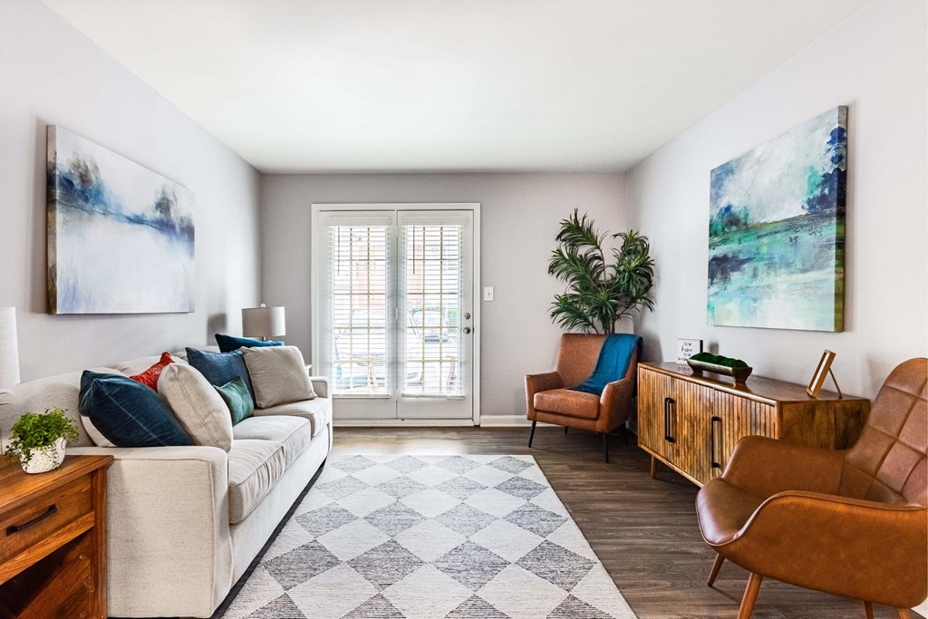 a living room with a couch and chairs and a door to a balcony