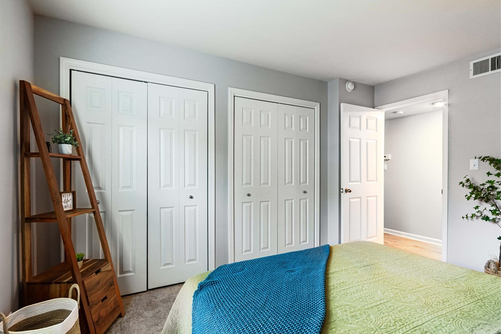 a bedroom with two closets and a bed with a blue blanket