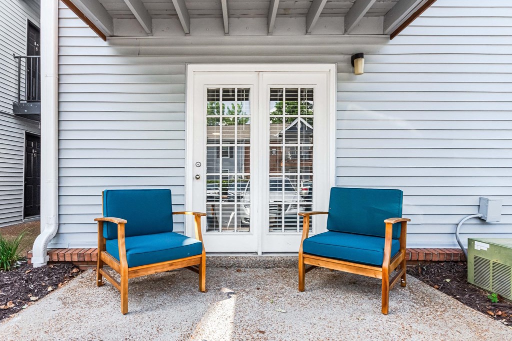 two blue chairs sitting in front of a white house