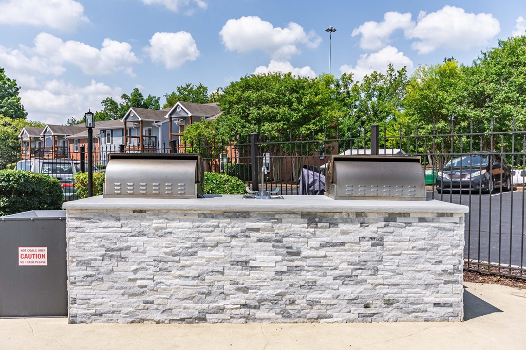 the clubhouse has a stone bar with two grills and a fence