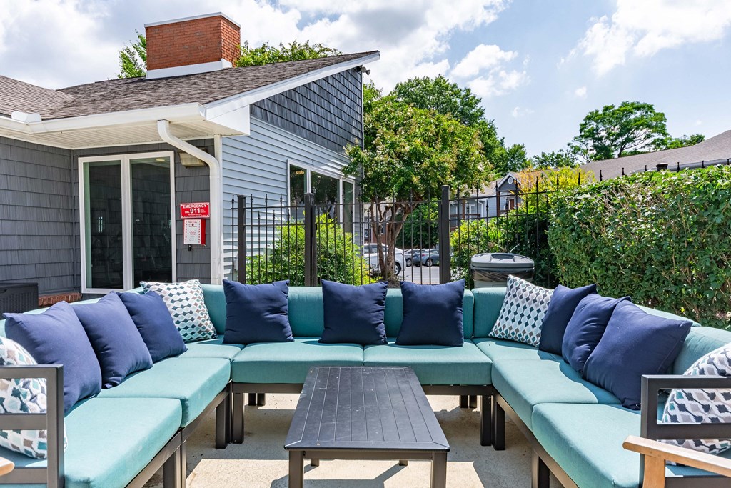a patio with blue couches and a table and a house