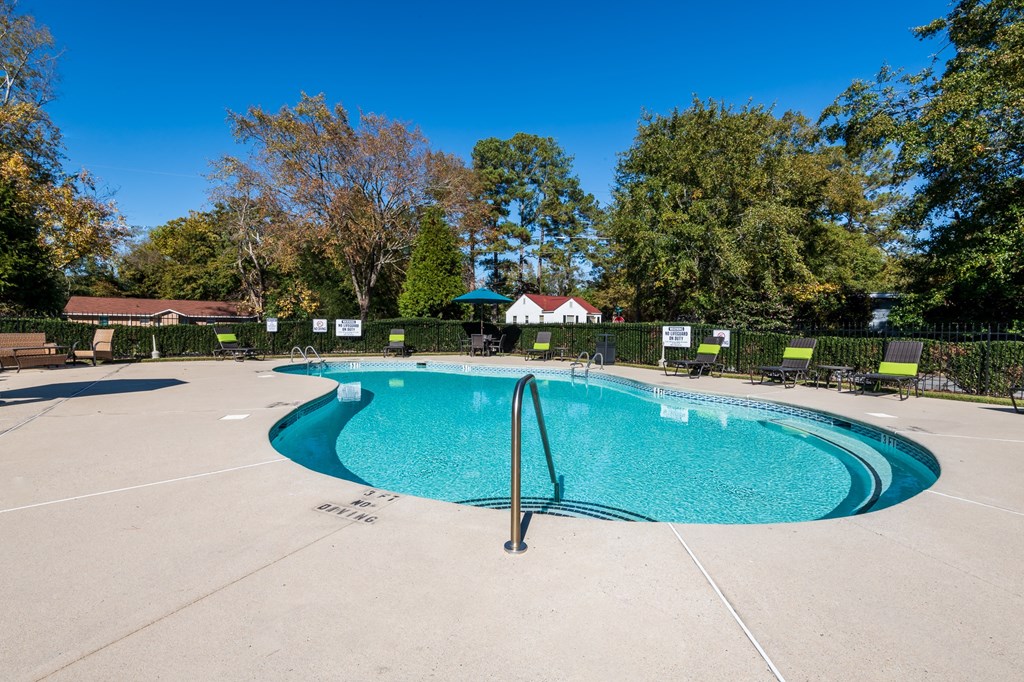 a resort style pool with chairs around it and trees