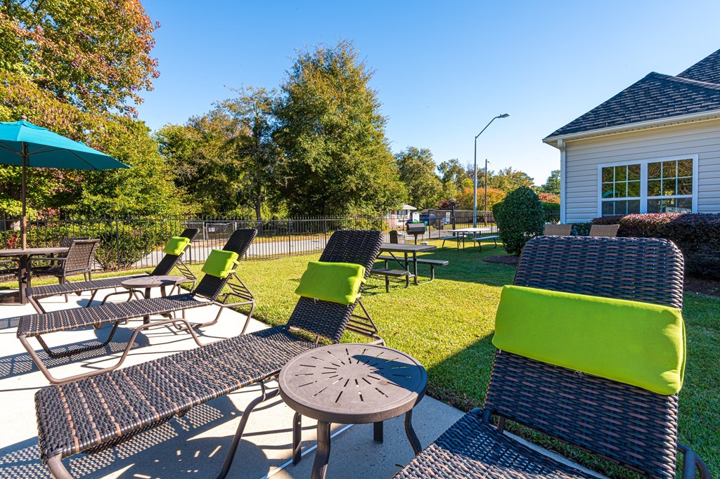 a sunny backyard with tables and chairs and a house