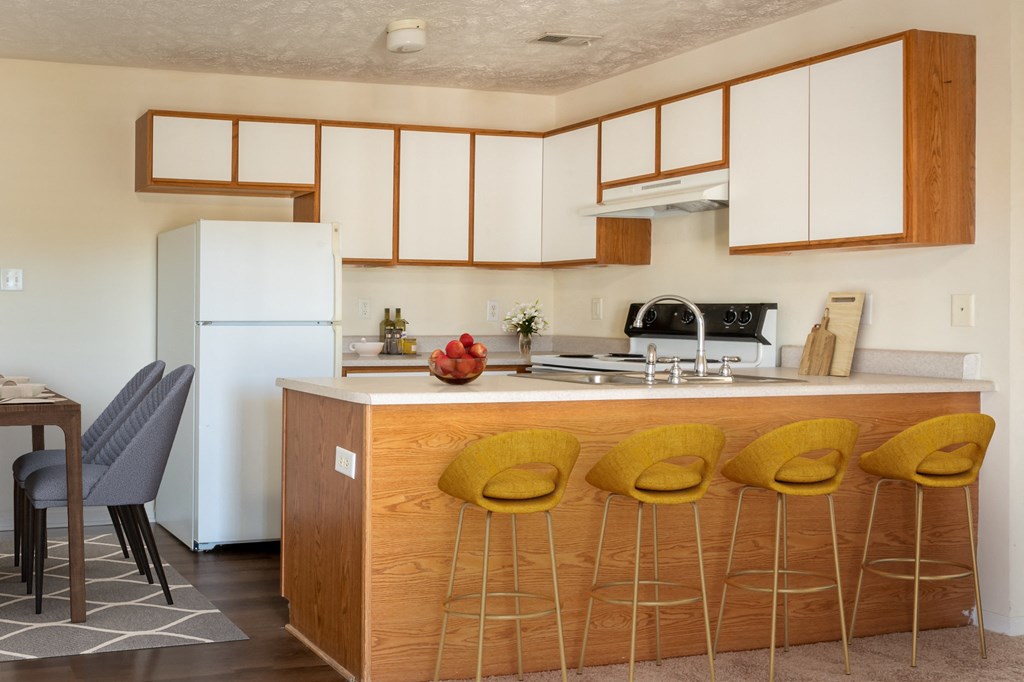 a kitchen with white cabinets and a counter with yellow chairs