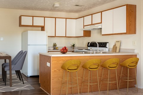 a kitchen with white cabinets and a counter with yellow chairs