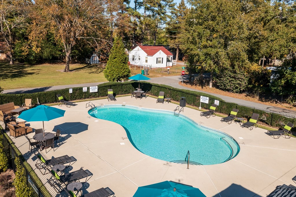 an aerial view of a pool and patio with umbrellas and chairs around it