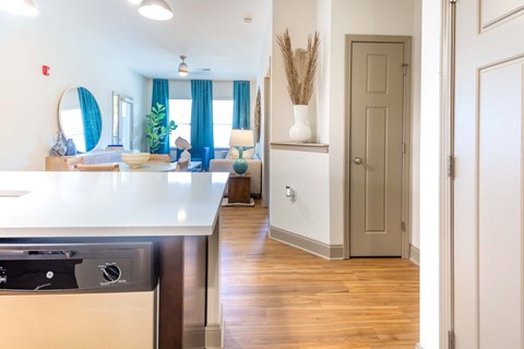 a kitchen and living room with blue curtains and a white counter top