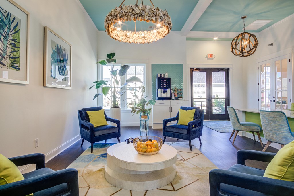 a living room with blue chairs and a round table and a chandelier