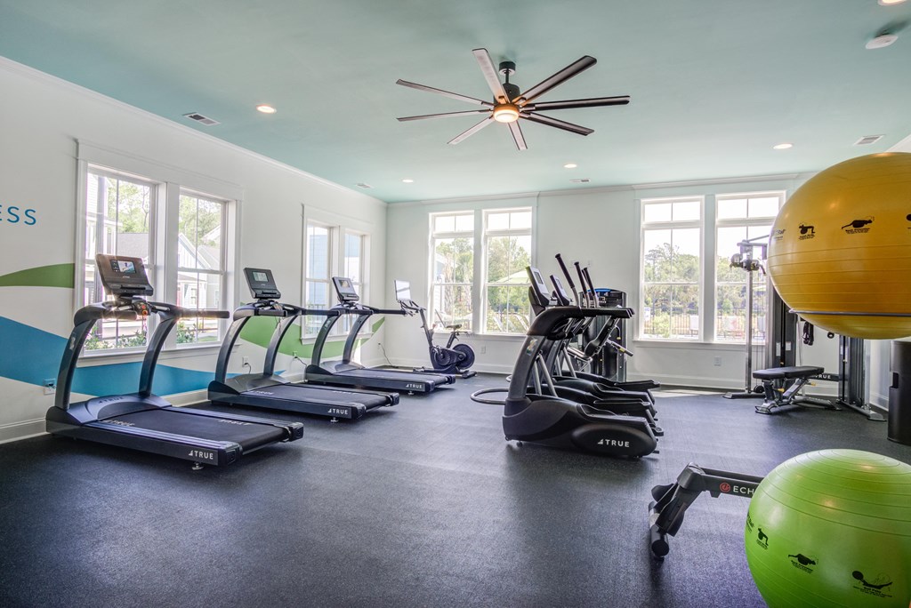 a gym with cardio equipment and a ceiling fan