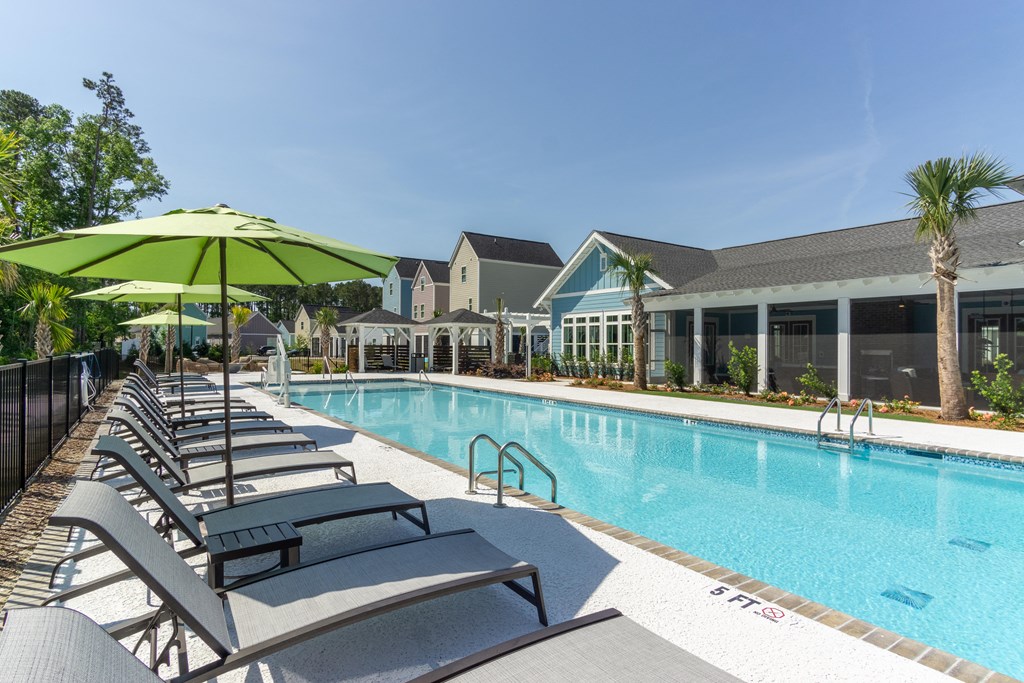 a swimming pool with lounge chairs and a building in the background
