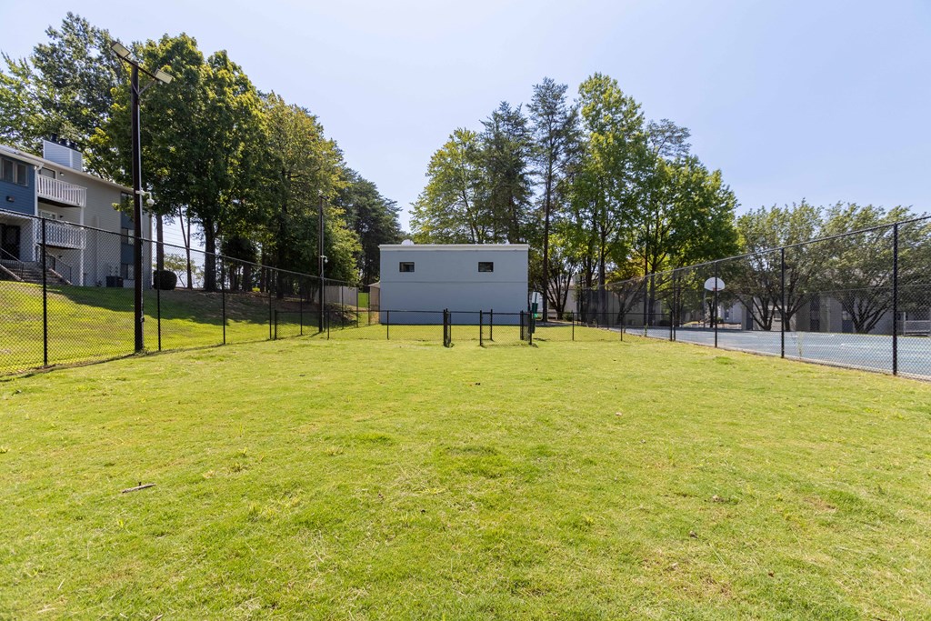 A grassy field with a fence and trees in the background at Enclave at 38 Twenty Two Apartments in Greensboro, NC
