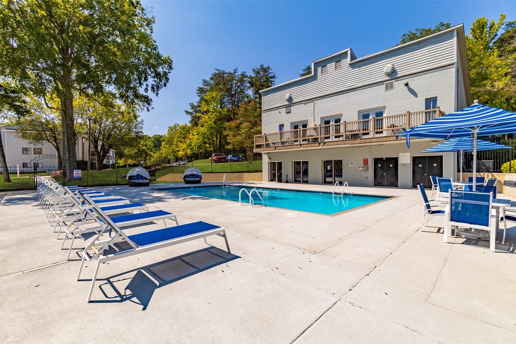 A pool area with sun loungers and a building in the background Enclave at 38 Twenty Two Apartments in Greensboro, NC