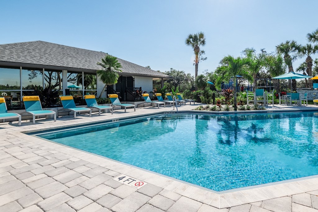 a resort style pool with lounge chairs and umbrellas
