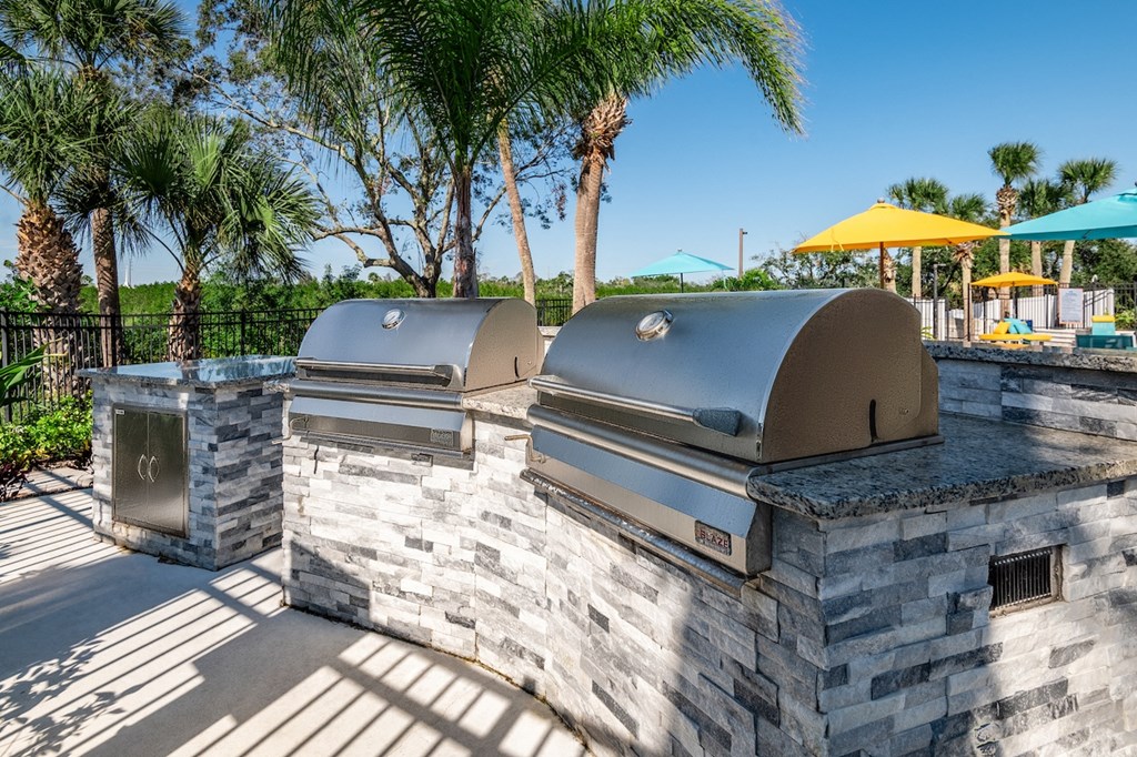 a bbq area with two grills and a table with umbrellas in the
