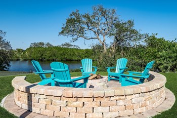 a fire pit with three adirondack chairs and a lake in the background - Photo Gallery 21
