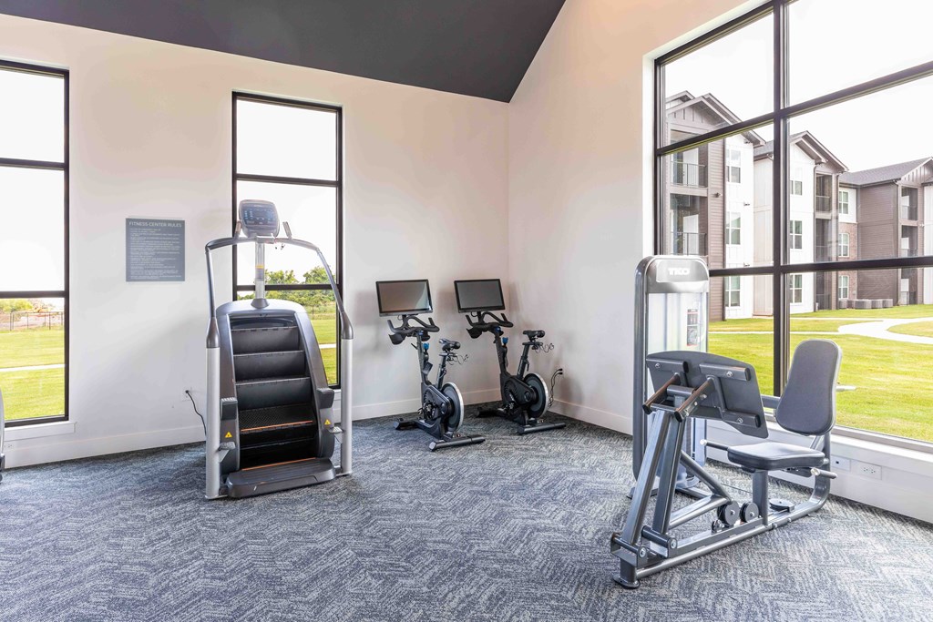 a gym with cardio equipment and windows in a building