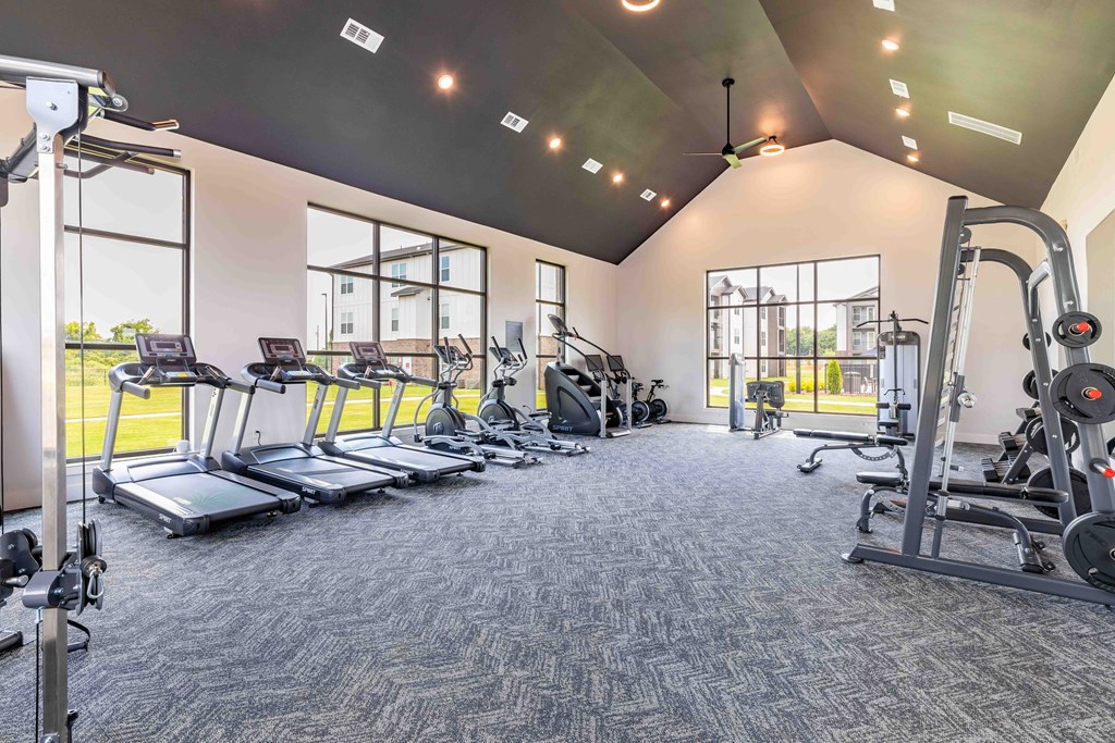 a gym with cardio equipment and windows in a building