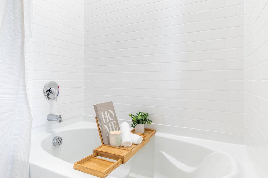 a white bathtub with a wooden tray with candles and a sign in the tub