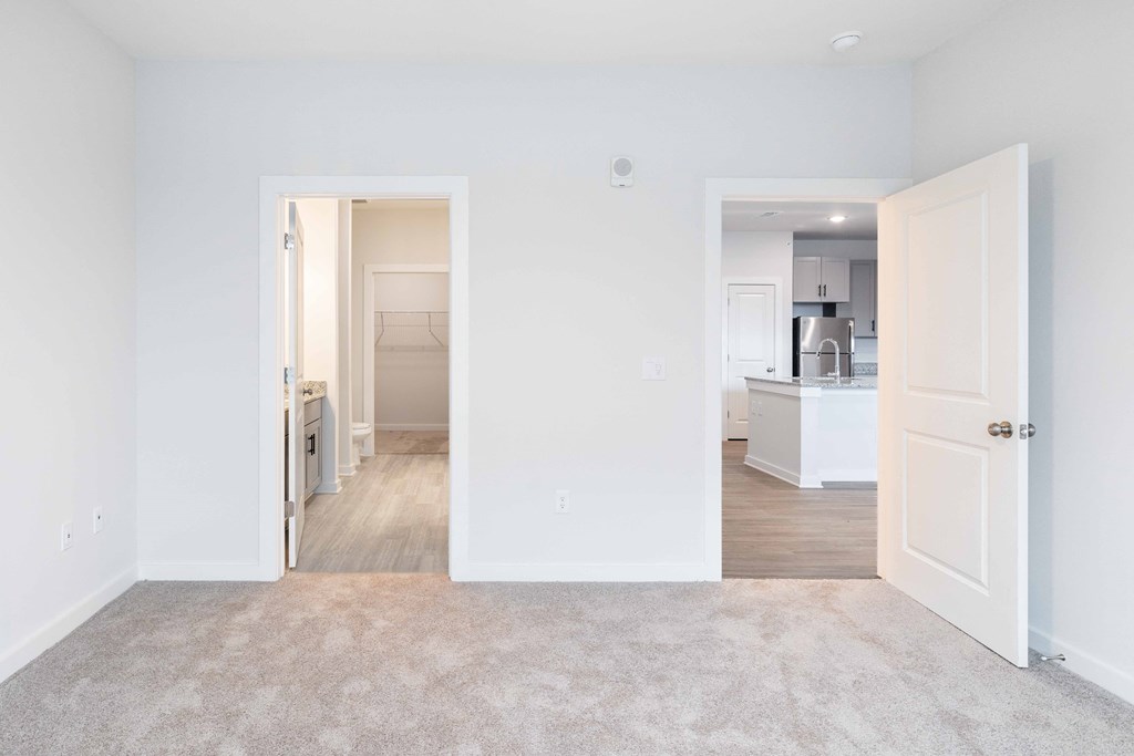 a living room with a carpet and a door to a kitchen