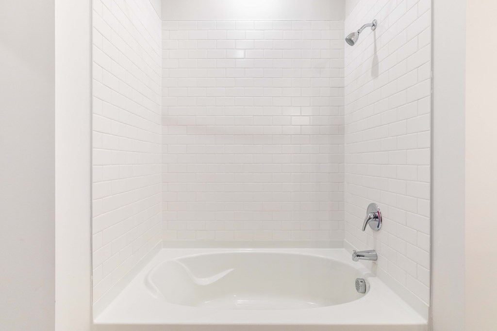 a small white bathroom with a tub and a shower