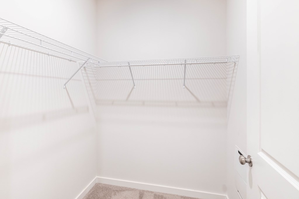 an empty closet in a home with white walls and a white door