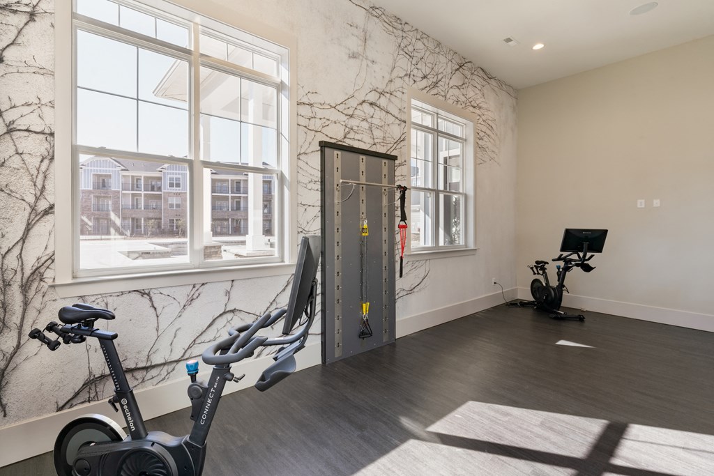A room with a wall mural, a treadmill, and a stationary bike.