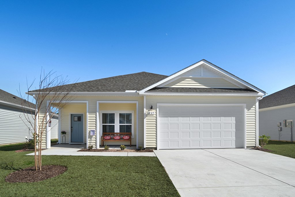 A cream colored home  with a white garage door at 15 at Heron apartments in Longs, SC.