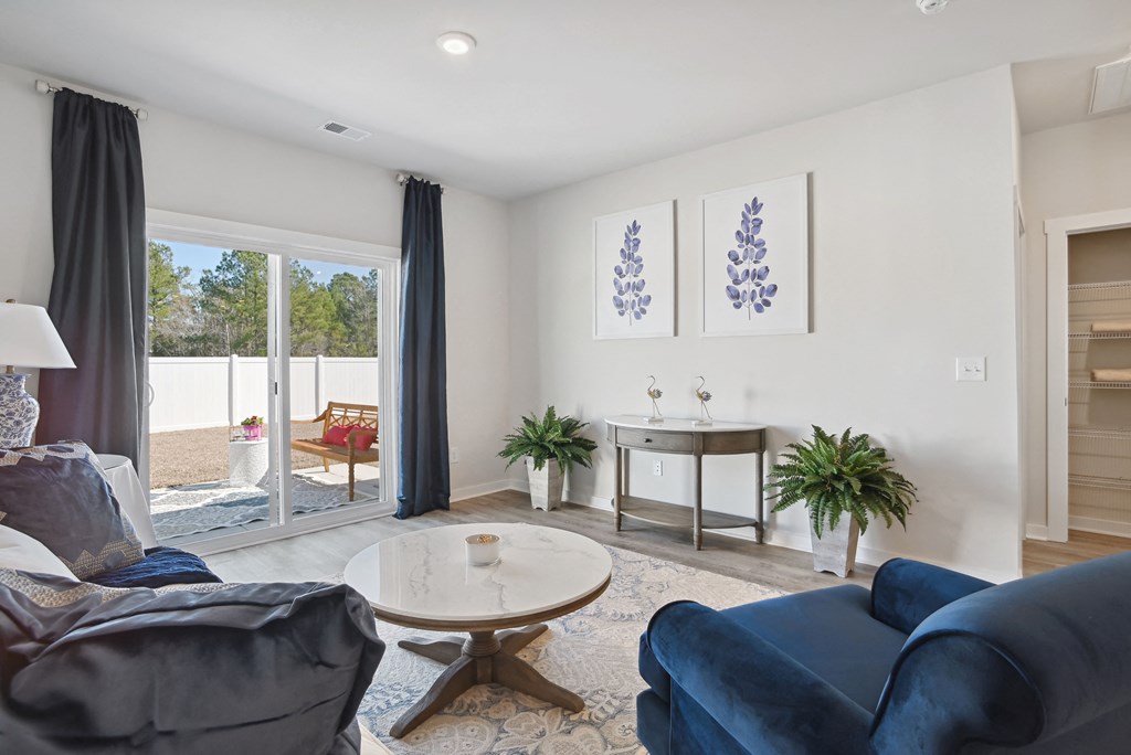 A living room with couches and a coffee table and sliding glass doors at 15 at Heron Apartments in Longs, SC.