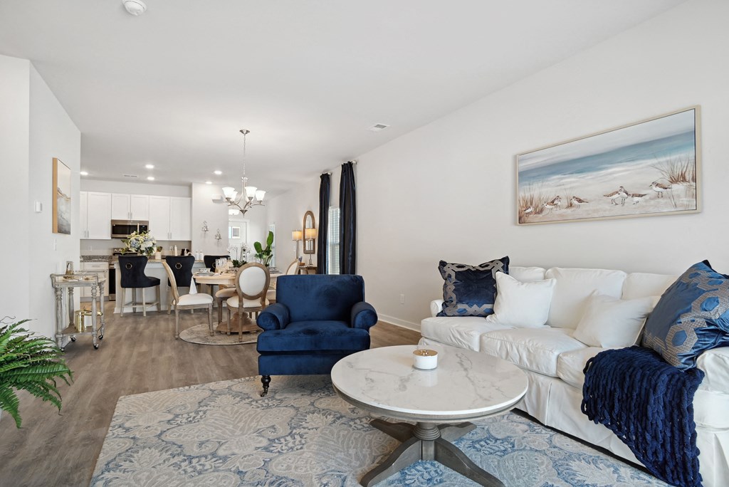 A living room with a couch and a chair and a dining table at 15 at Heron apartments in Longs, SC.