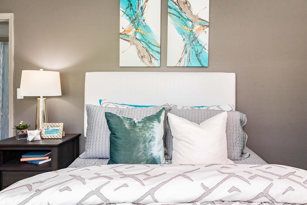 a bedroom with a bed with pillows and artwork on the wall