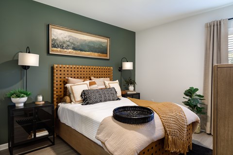 A bedroom with a bed, nightstands, and a painting on the wall.