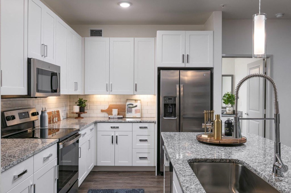 a kitchen with granite counter tops and a stainless steel refrigerator
