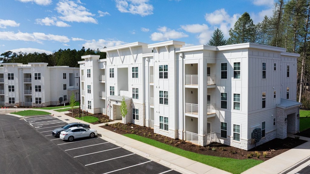 A white apartment building with a car parked in front.