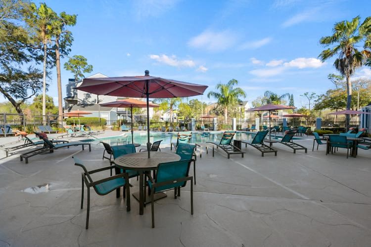 a patio with tables chairs and umbrellas and a pool