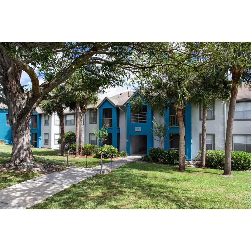 exterior view of apartments with a sidewalk and trees