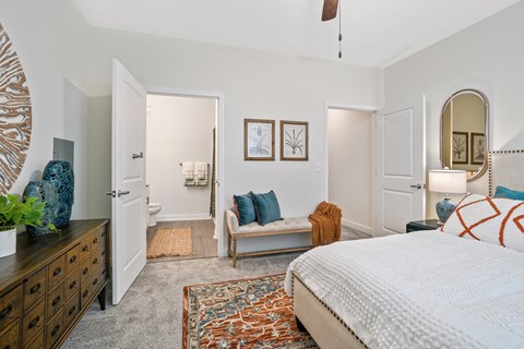 a bedroom with a bed and a dresser and a bathroom