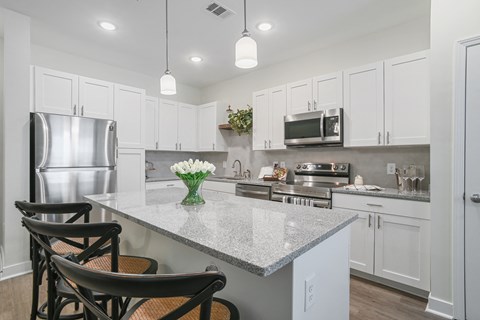 a kitchen with white cabinets and a marble counter top