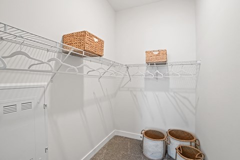 a walk in closet with a mirrored wall and two baskets on the shelves