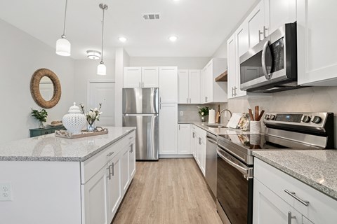 a white kitchen with stainless steel appliances and white cabinets