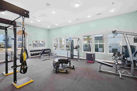 a gym with weights and other equipment in a room with windows