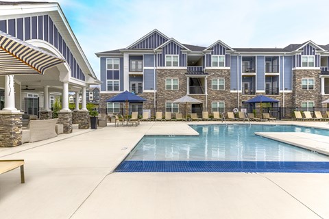 A large swimming pool in front of a multi-story apartment building.