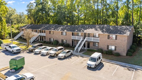 Front parking lot with cars and the complex building in the background.