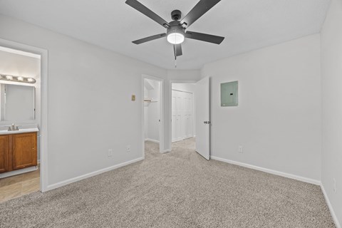 A spacious room with a ceiling fan and carpeted floor.