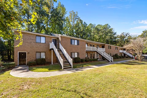 Exterior of complex brick building with three sets of stairs going down into a green grass lawn.