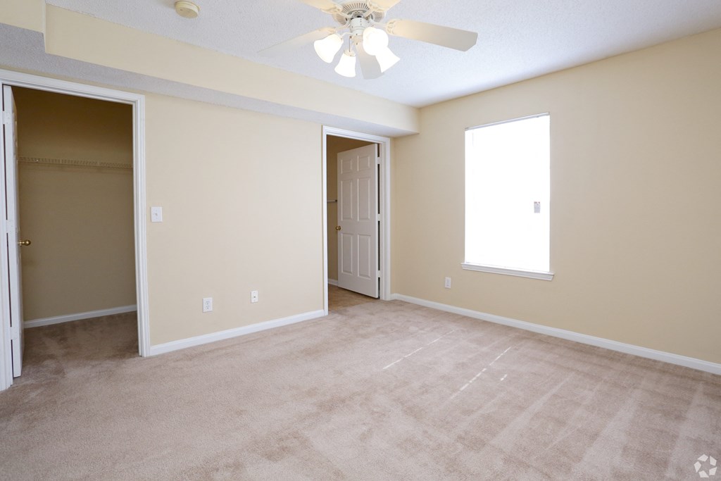 an empty living room with a closet and a ceiling fan