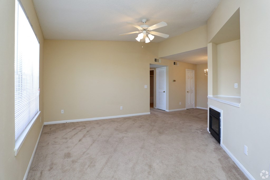 an empty living room with a fireplace and a ceiling fan